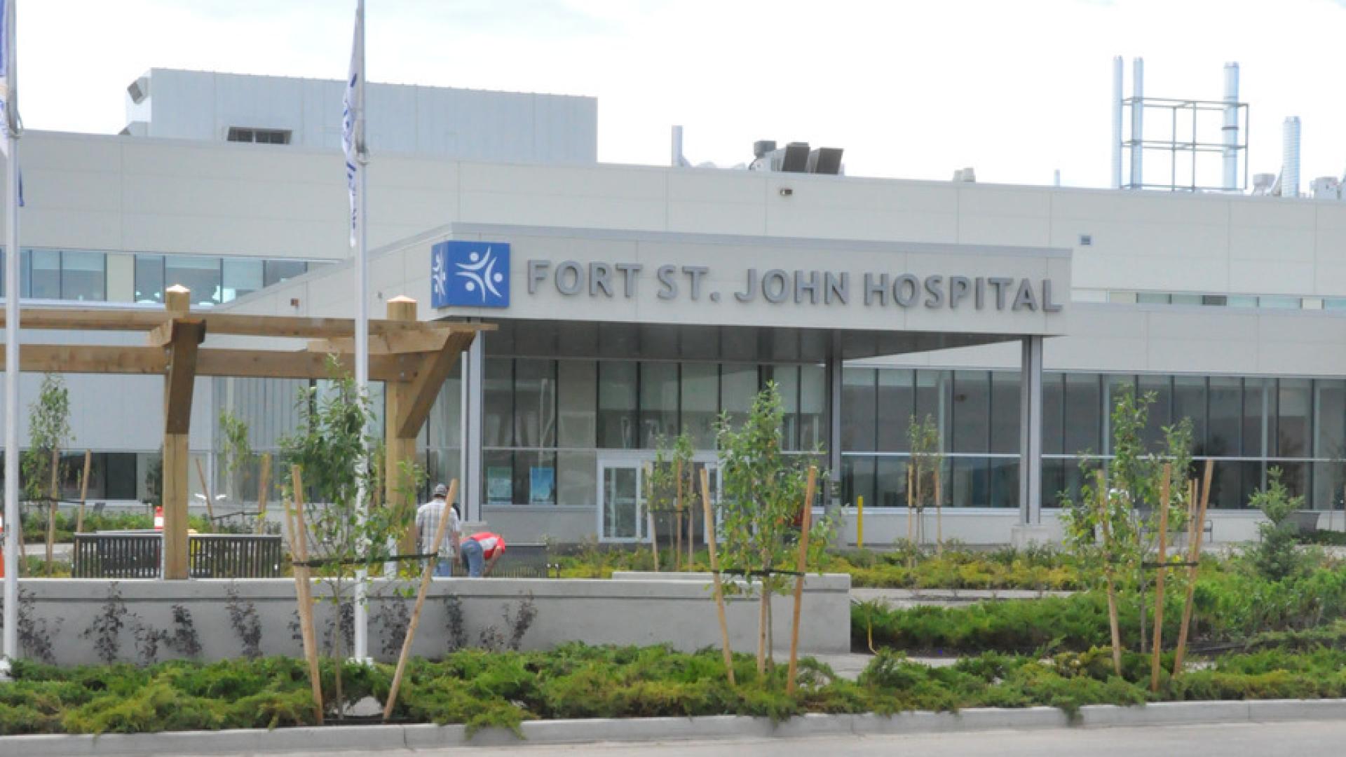 Front view of Fort St. John Hospital with a modern facade, greenery, and a wooden pergola in the foreground.