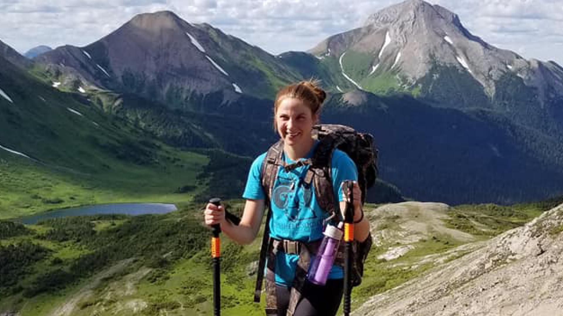 Jocelyn stands at the peak of a mountain.