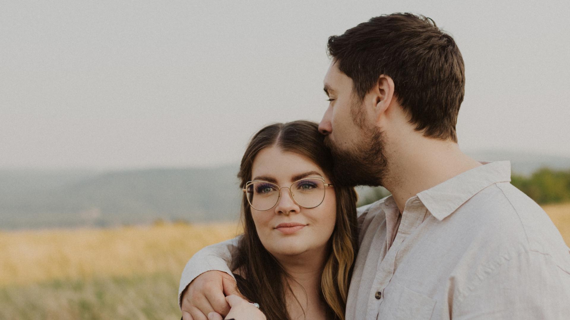 Whitney faces the camera with her husband in a field.