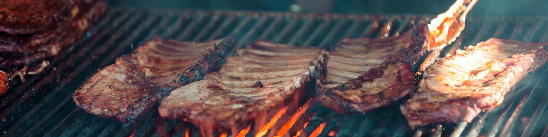 Ribs cook on a BBQ.