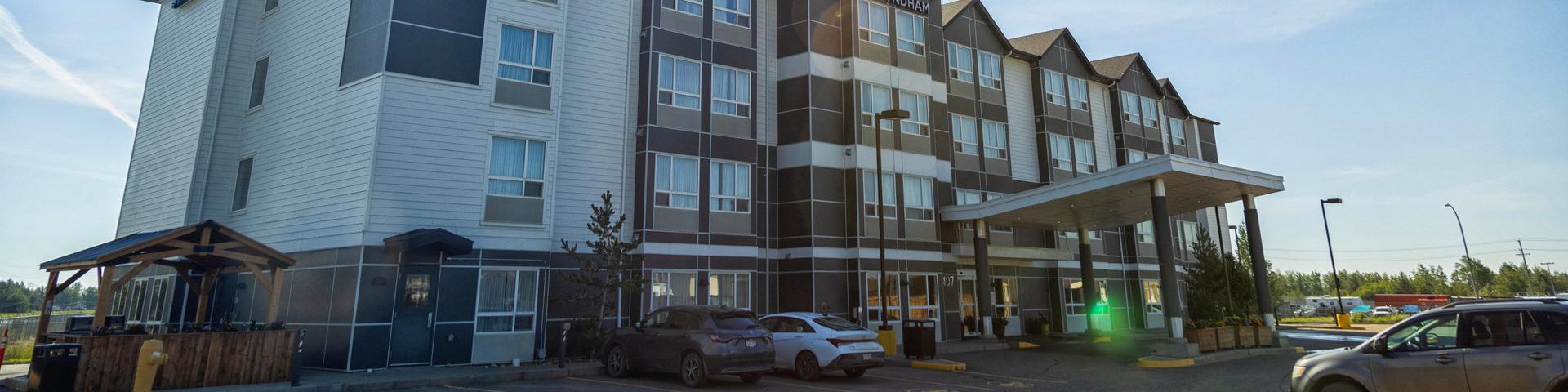 A hotel in Fort St. John with several vehicles in the parking lot.