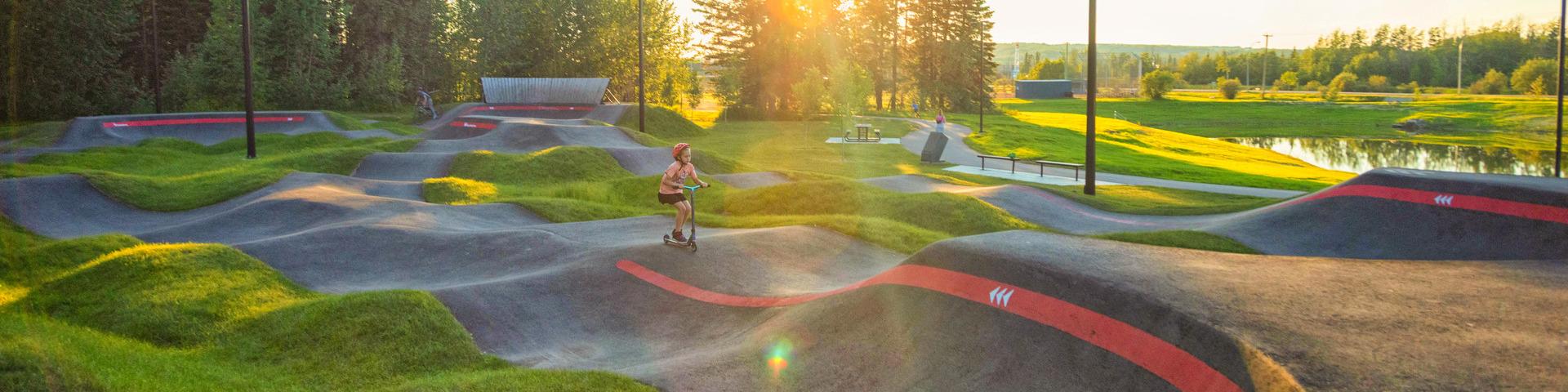 A child scooters across the Pump Track at Kin Park.
