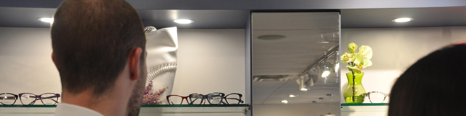 An optometrist stands near a display of glasses.