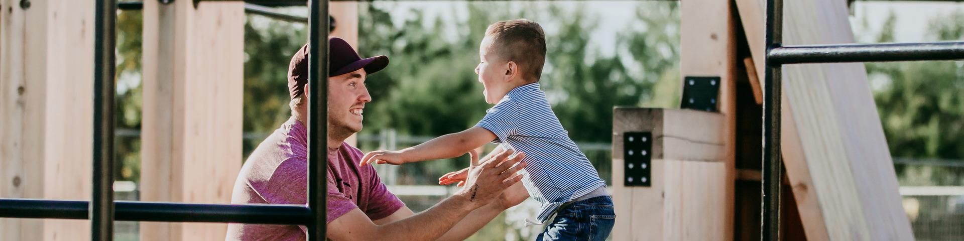 A child jumps into his father's arms at the Parkour Park.