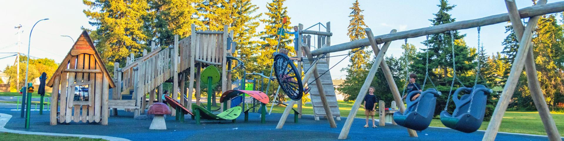 Kids play on the Kin Park playground equipment.